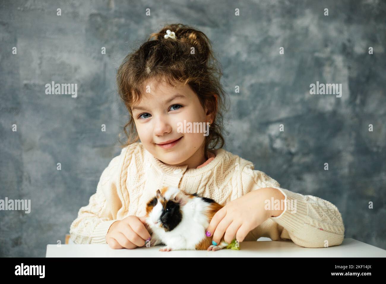Cheerful little girl of kindergarten age play with white-orange-black