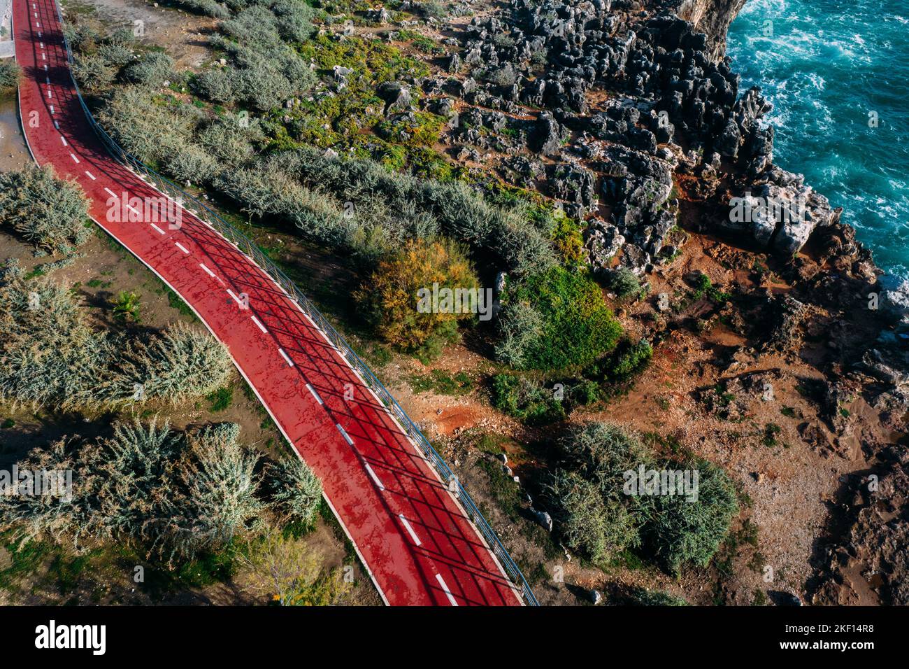 Aerial drone view of red cycling path hugging the Cascais, Portugal coast on a sunny day Stock Photo