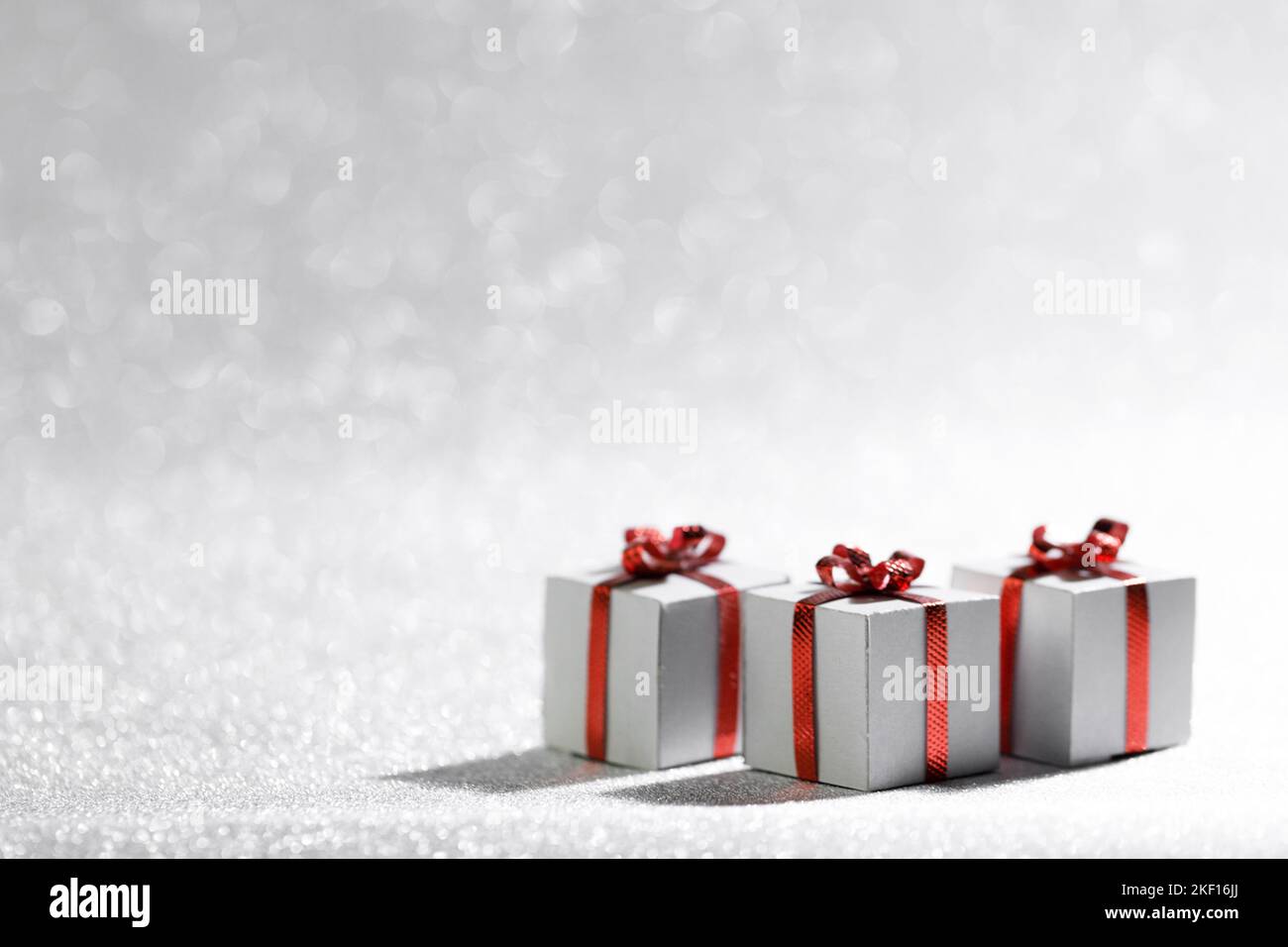 Small decorative Christmas gift boxes with red ribon bows on silver