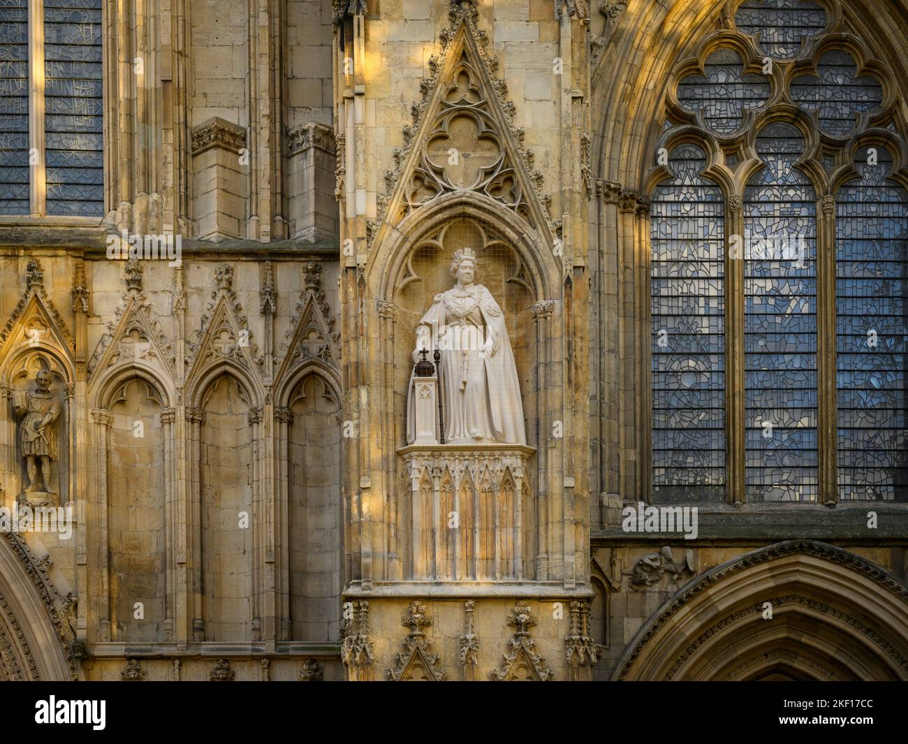 Elizabeth 2 limestone statue standing on high niche wearing ceremonial dress (orb & sceptre) - west front, York Minster, North Yorkshire, England UK. Stock Photo