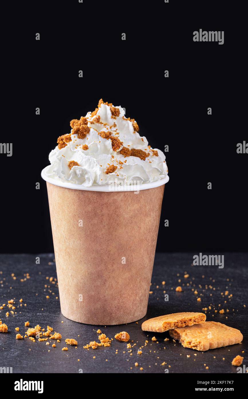 Paper cup with hot drink with whipped cream on dark background