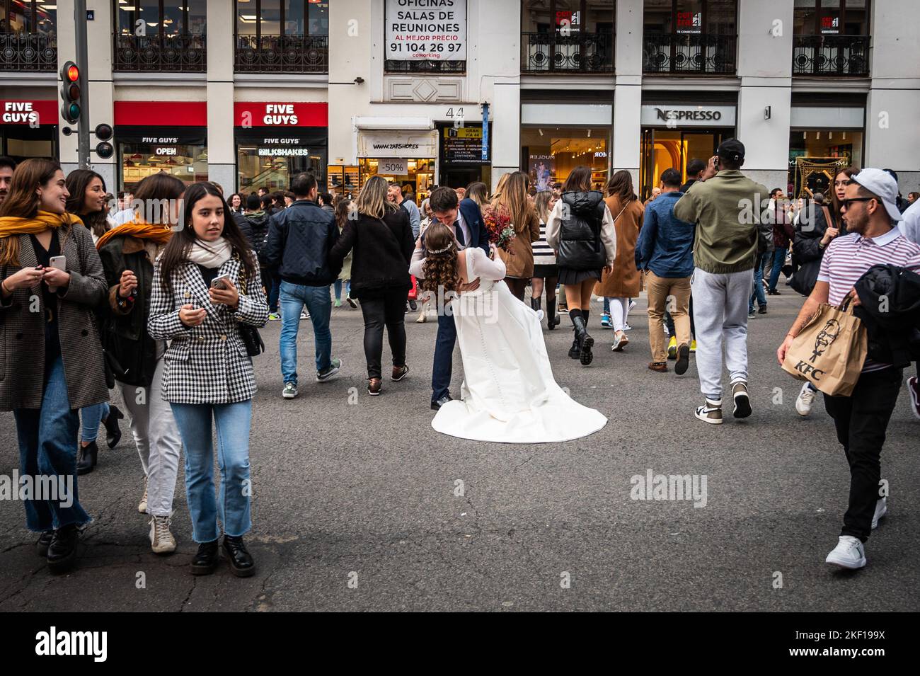 A bride and a groom kissing in the middle of a street in downtown ...