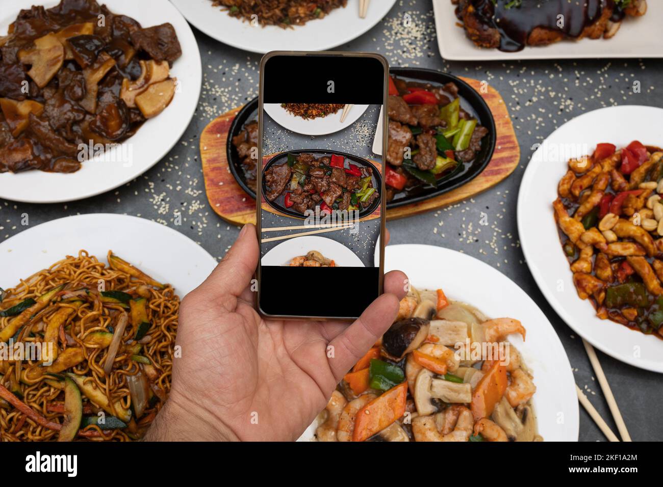 A hand taking a picture of oriental food together with a mobile phone Stock Photo