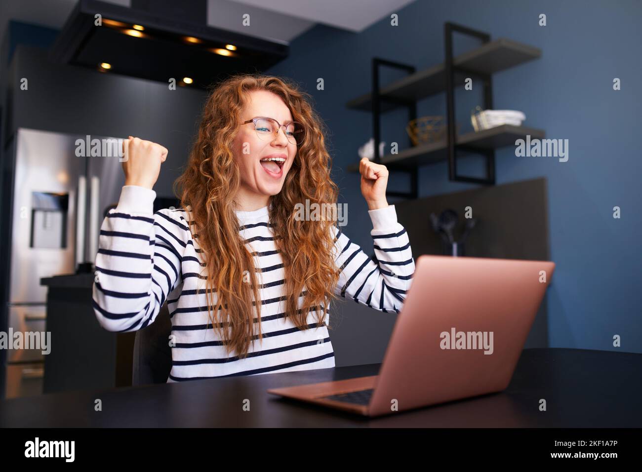 Happy woman checks e-mail, good news about success on laptop. Female rejoice, celebrate visa approval, winning prize and money, project completion Stock Photo