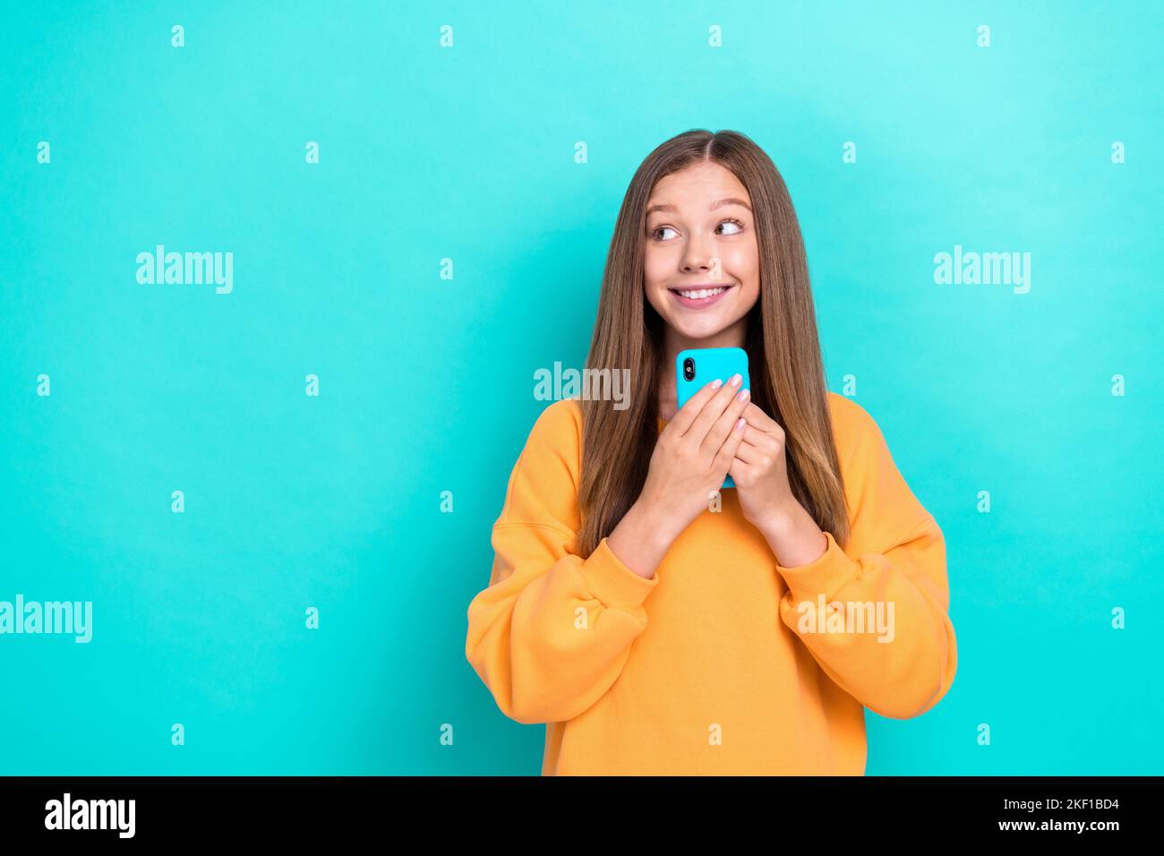 Photo of excited young pretty cute lady teenager hold her new iphone pro max look dreamy empty space new ad isolated on cyan color background Stock Photo