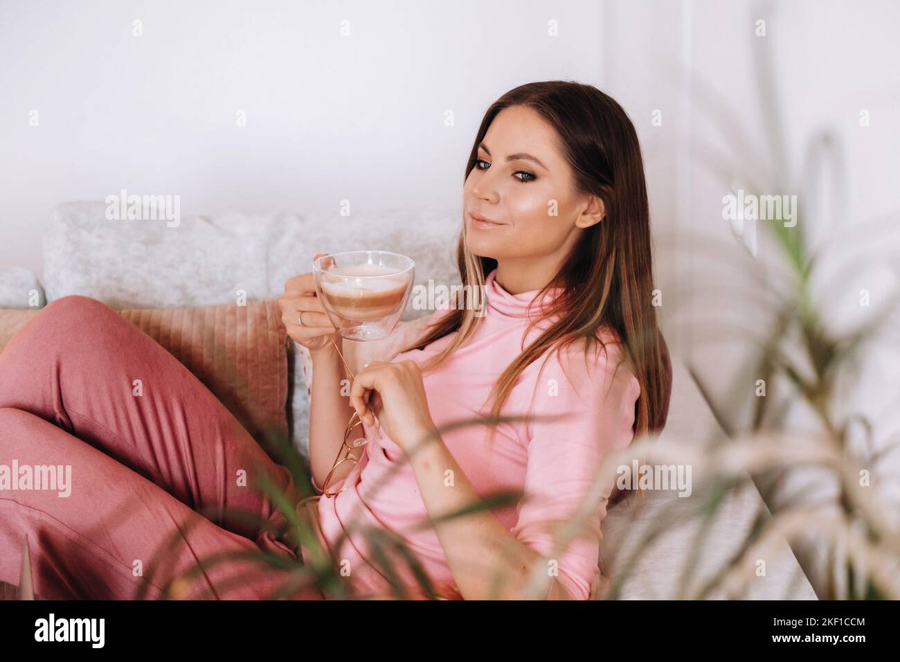 relaxed girl in the morning in pajamas at home drinking coffee .Inner peace.The girl is sitting comfortably on the sofa and drinking coffee dreaming Stock Photo