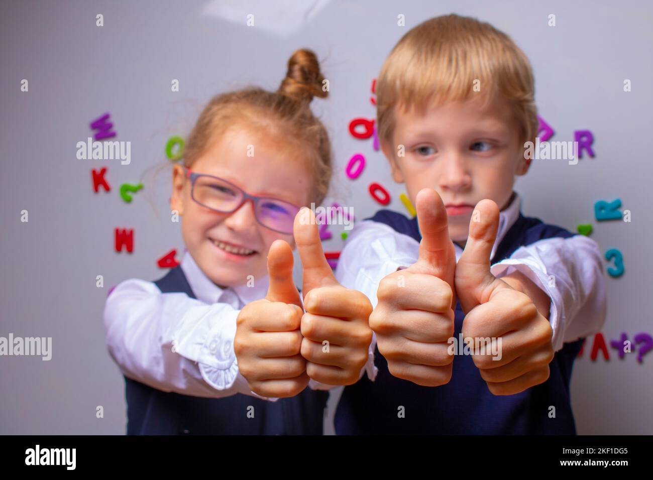 brother and sisiter showing thumbs up together in the classroom Stock Photo