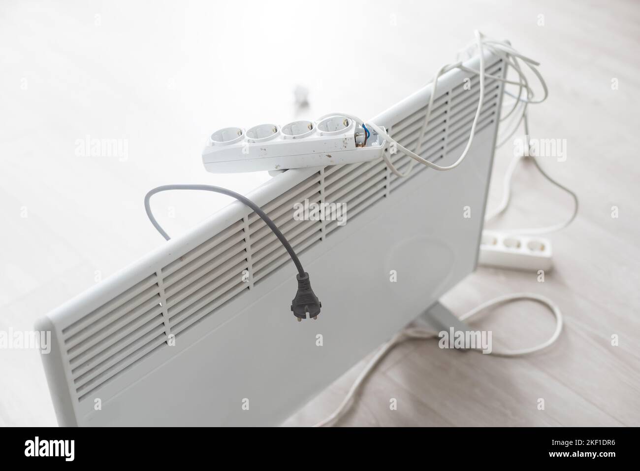 Electric heater plug inserted into extension cord. White radiator for
