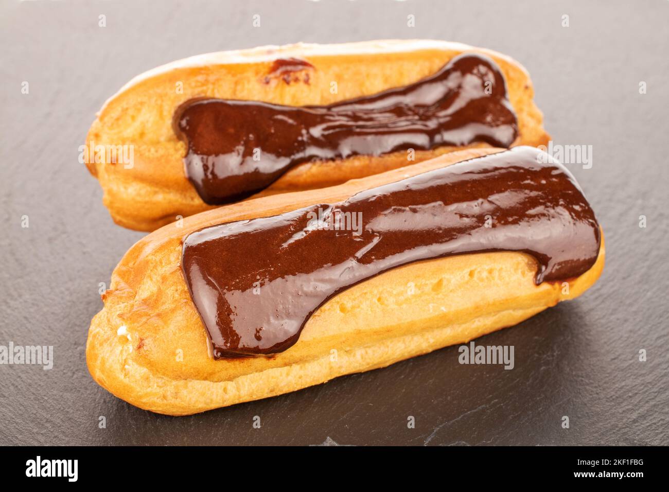 Two sweet eclairs on slate stone, macro. Stock Photo