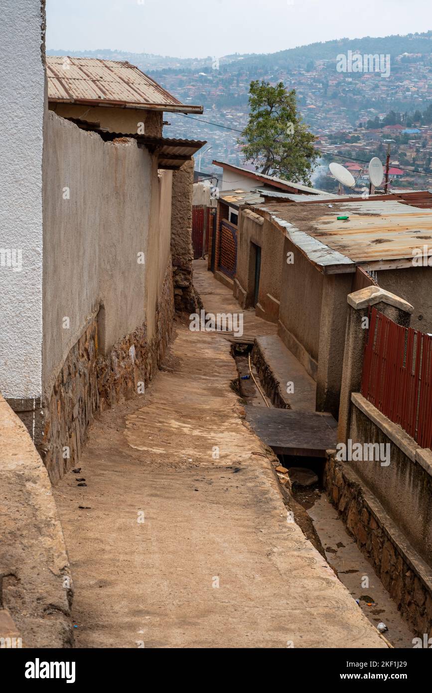 Kigali, Rwanda - August 17 2022: A narrow dirt alleyway and gutter between low-cost housing in Nyamirambo, Kigali. Stock Photo