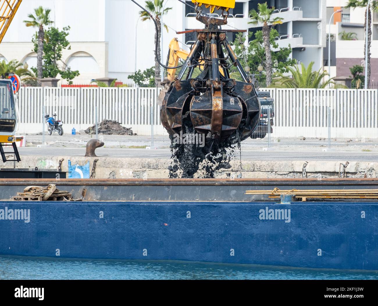 Dredger dredging oily silt from docks to increase depth for larger ships. Stock Photo