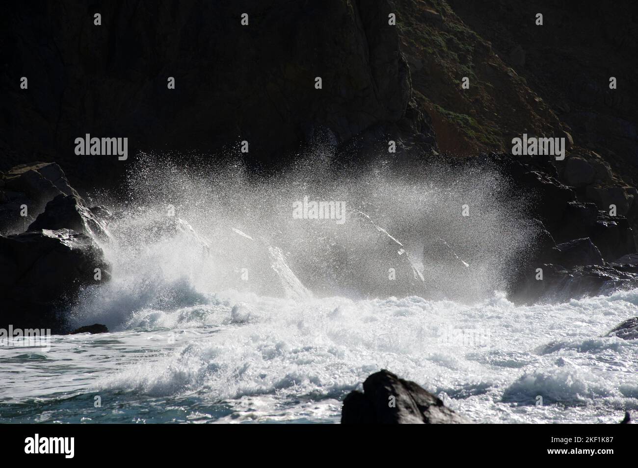 Crashing Wave splashing against rock Stock Photo