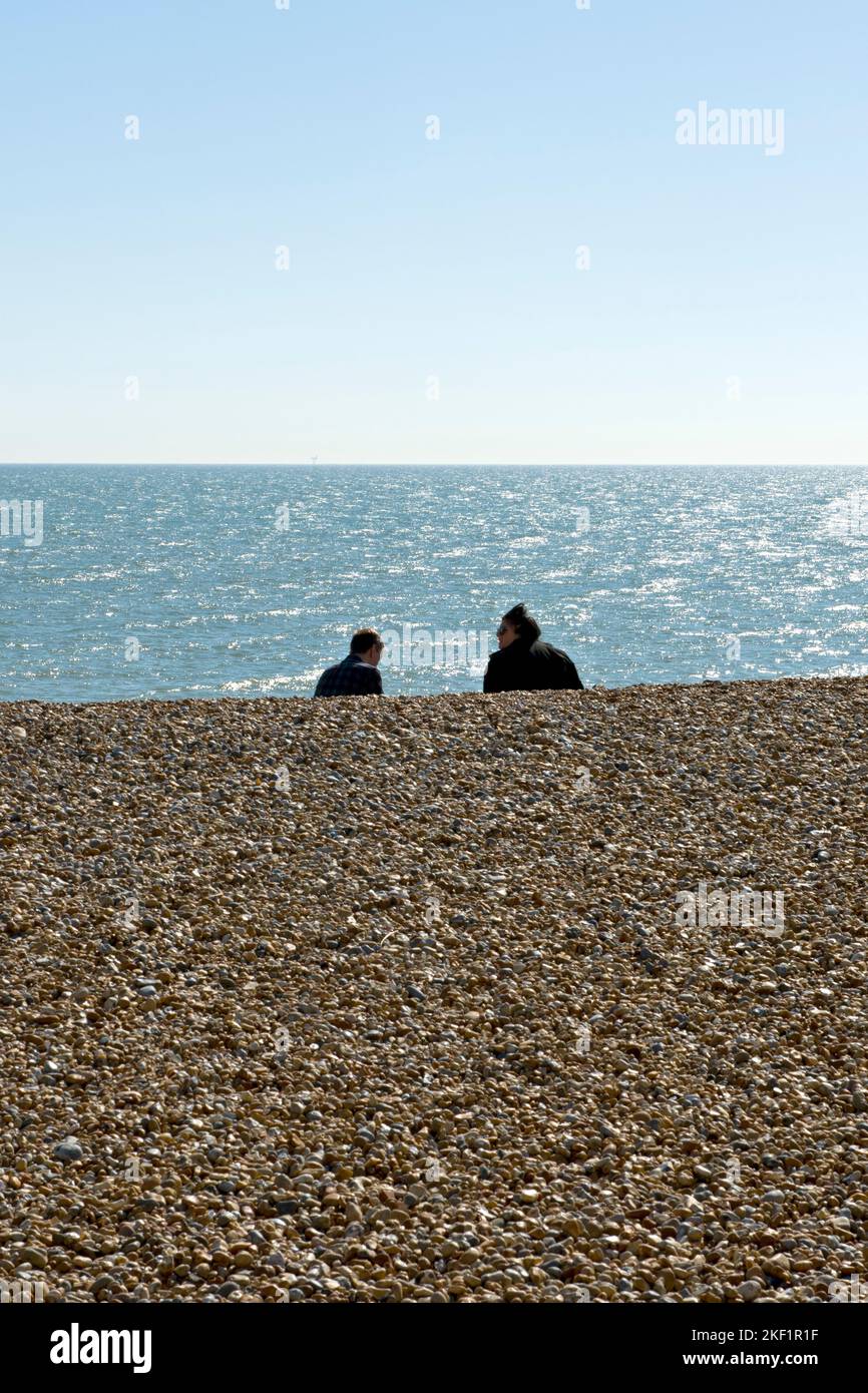 A couple look out to sea from the beach at Eastbourne, East Sussex, UK Stock Photo
