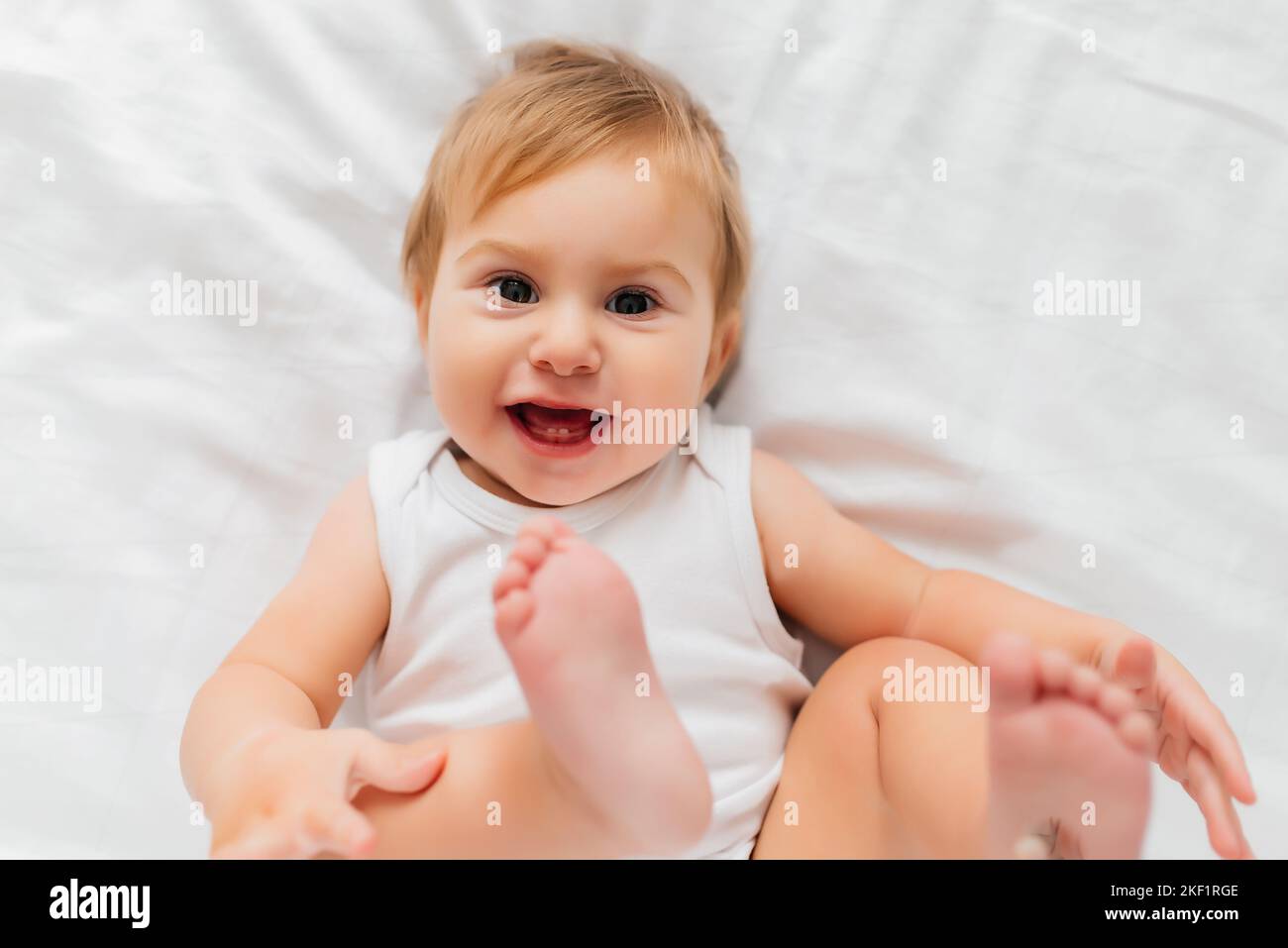 cute happy 8 month old baby girl in diaper lying and playing Stock