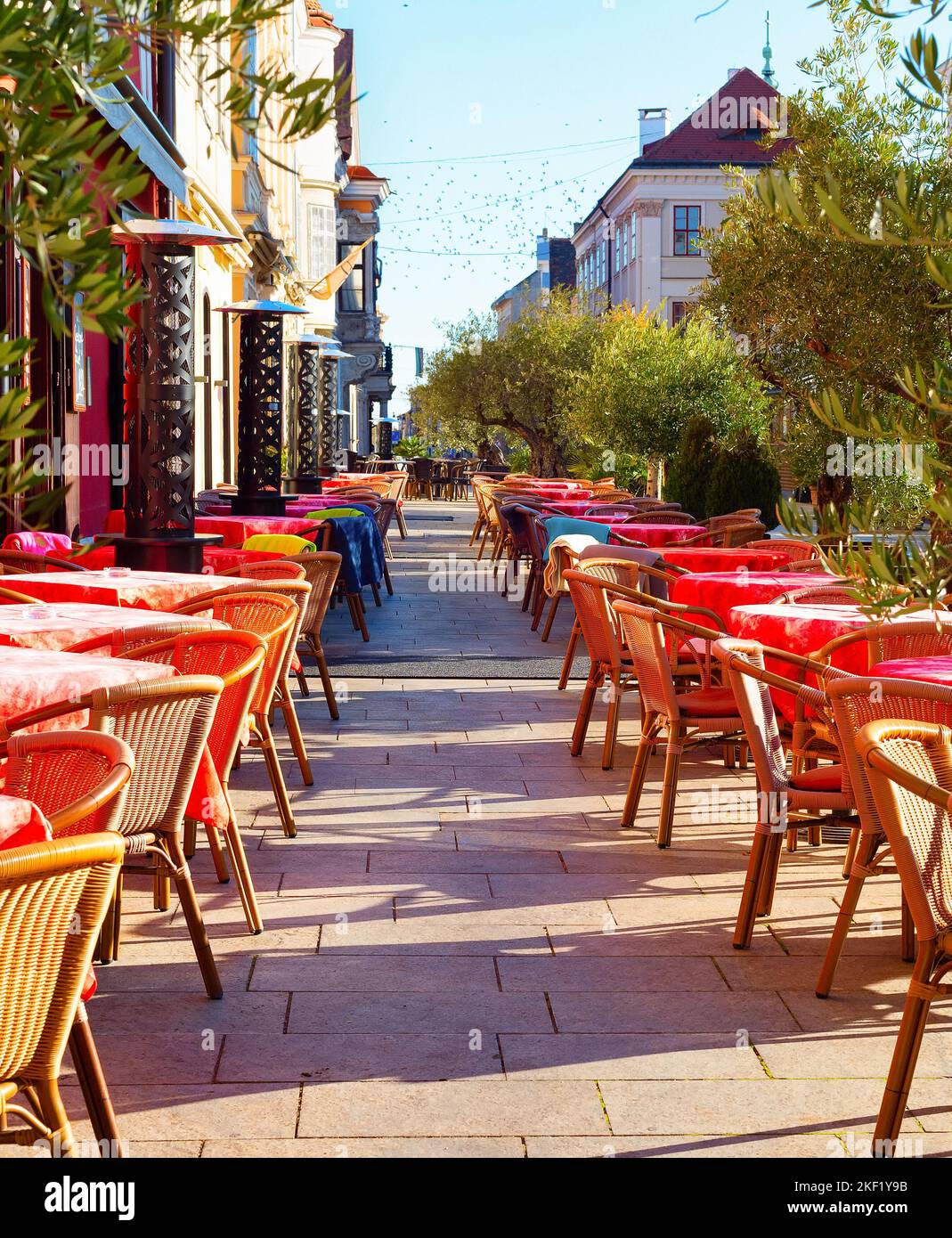 Tables with red cloths on outdoor terrace of restaurant on touristic street, Gyor, Hungary Stock Photo