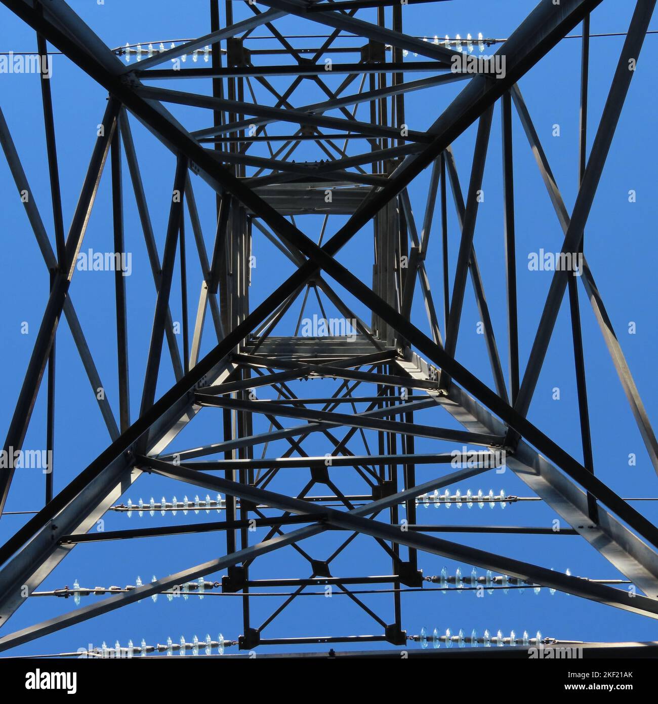 A low angle shot of high voltage transmission tower against a blue sky ...