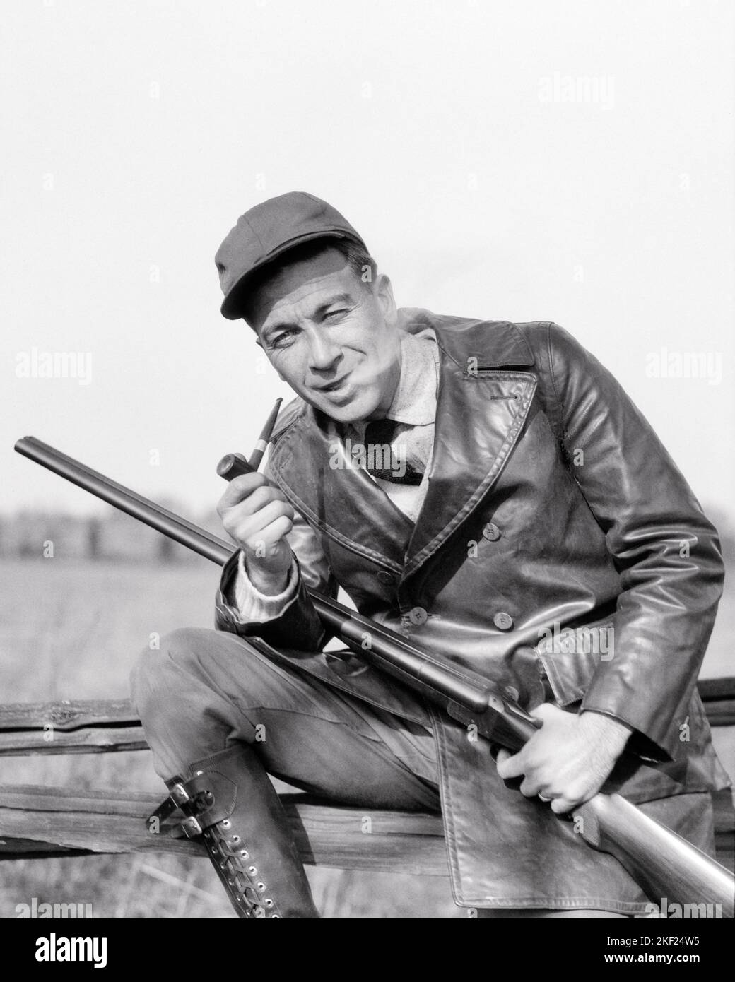 1920s OUTDOORSMAN WEARING LEATHER SHOOTING JACKET HOLDING A SHOTGUN SMOKING A PIPE SMOKE ESCAPING HIS MOUTH LOOKING AT CAMERA - g249 HAR001 HARS B&W HUNT EYE CONTACT ADVENTURE HIS PIPES STYLES TOBACCO BAD HABIT SMOKER NICOTINE ESCAPING CONCEPTUAL ADDICTIVE STYLISH OUTDOORSMAN FASHIONS FIREARM FIREARMS HUNTERS MID-ADULT MID-ADULT MAN SHOTGUNS BLACK AND WHITE CAUCASIAN ETHNICITY HAR001 OLD FASHIONED Stock Photo