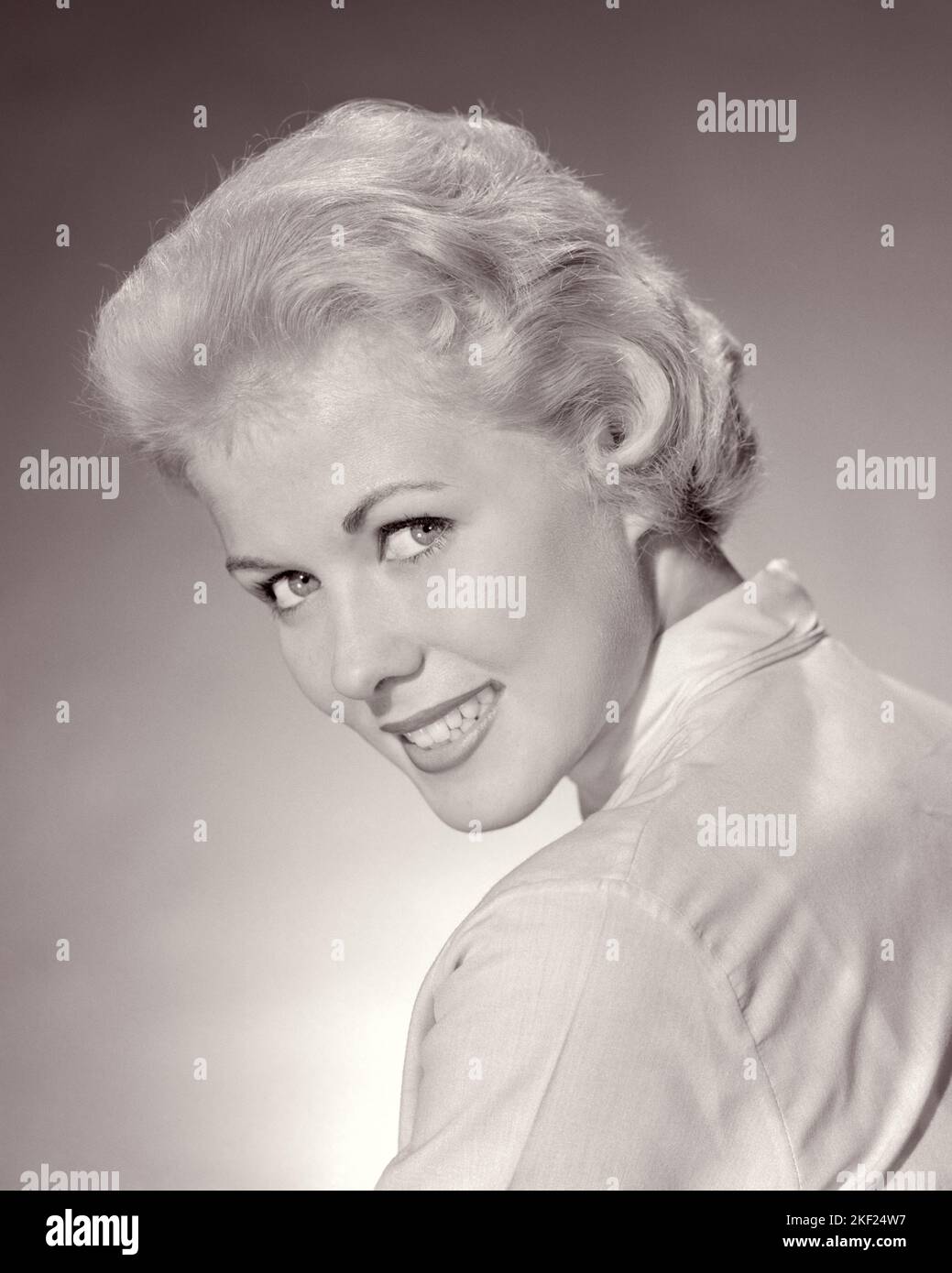 1950s PORTRAIT PRETTY TEEN GIRL SMILING WITH SHORT BLONDE HAIR LOOKING AT CAMERA OVER HER SHOULDER - g224 HAR001 HARS CONFIDENCE B&W EYE CONTACT PRETTY HAPPINESS HEAD AND SHOULDERS CHEERFUL JOYFUL STYLISH TEENAGED YOUNG ADULT WOMAN BLACK AND WHITE CAUCASIAN ETHNICITY HAR001 OLD FASHIONED Stock Photo