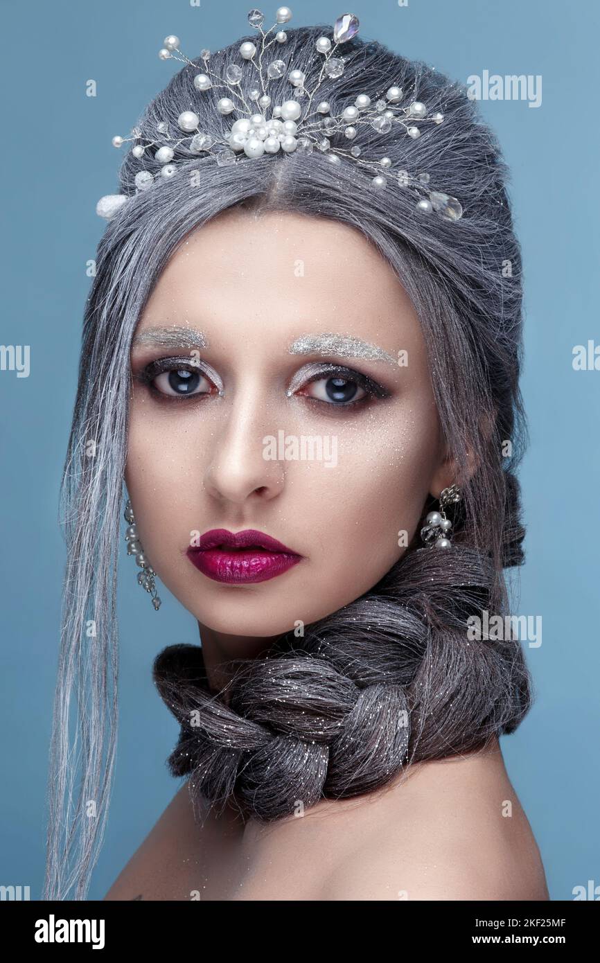Portrait of winter queen with tiara on blue studio background Stock Photo