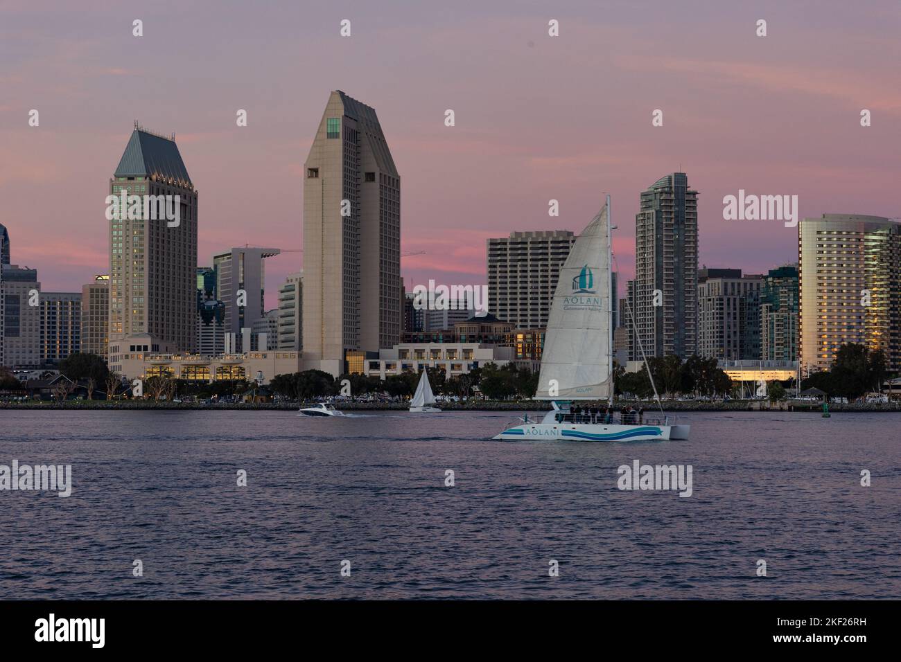 Sailboat enters San Diego bay at sunset with the skyline in the distance Stock Photo