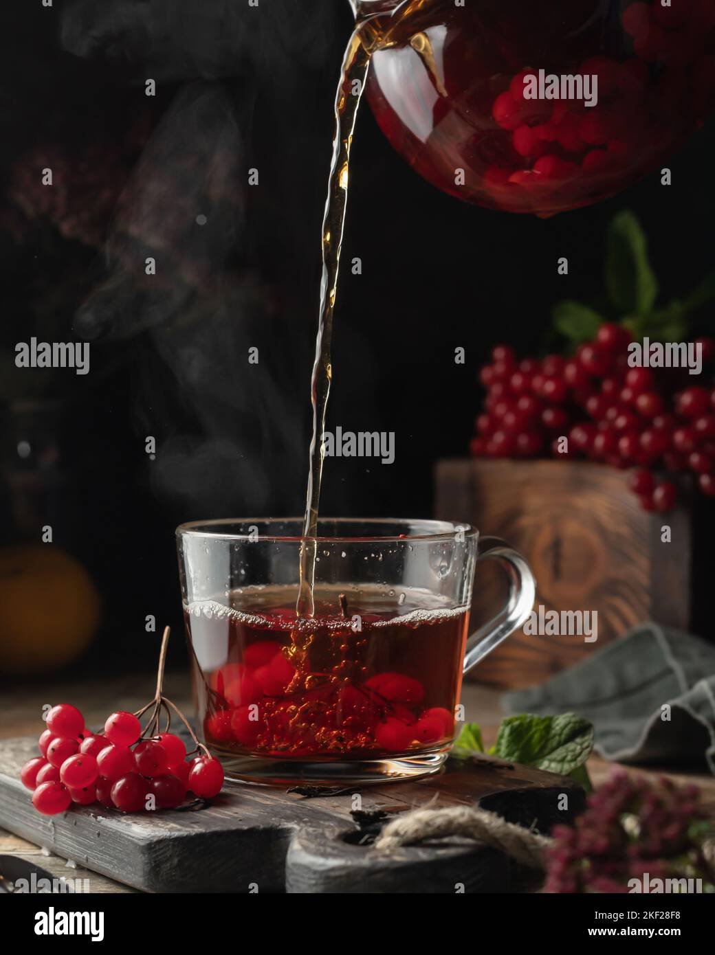 Viburnum tea is poured into a cup from a glass teapot with steam ...