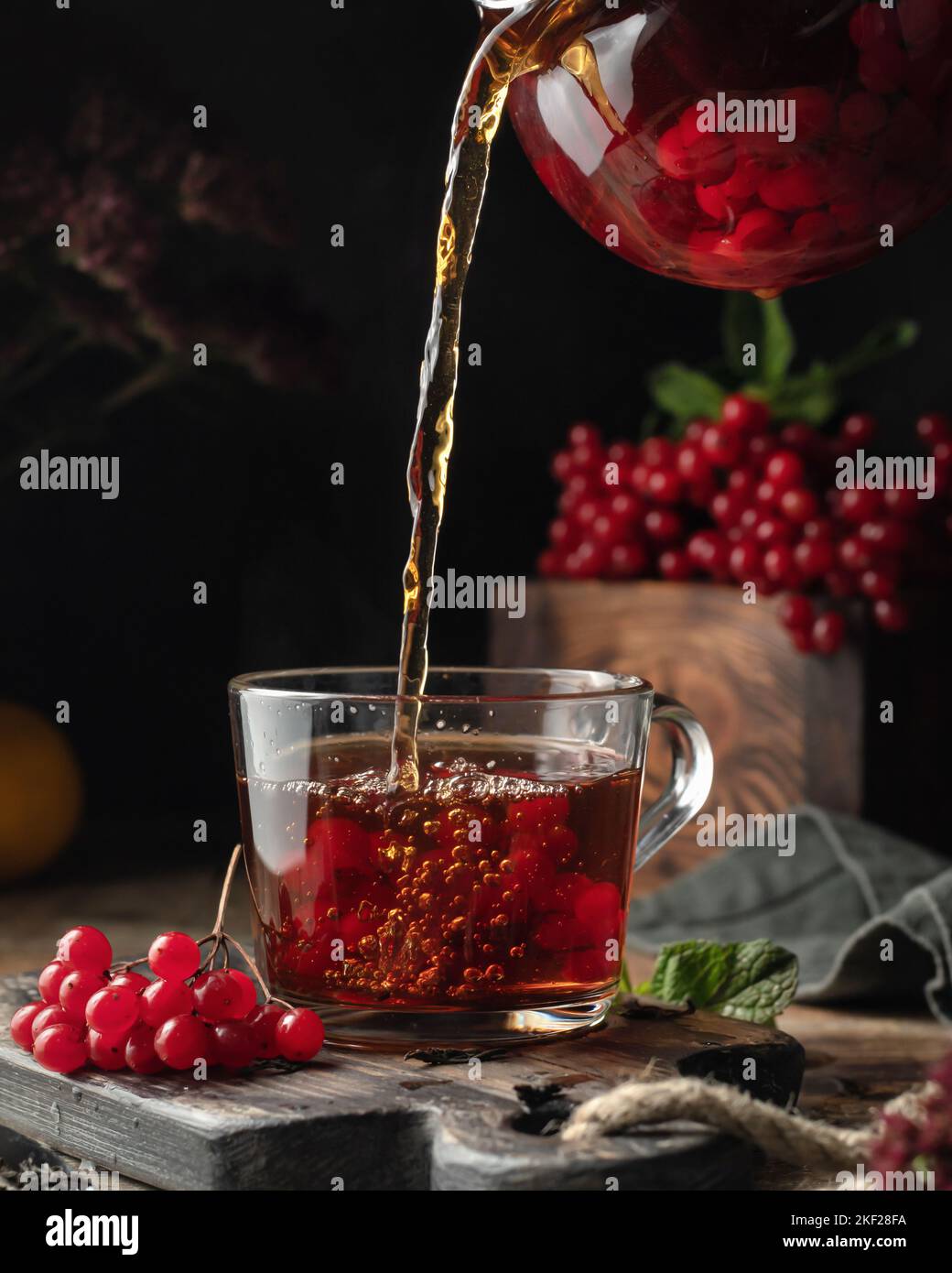 Viburnum tea is poured into a cup from a glass teapot, pouring process ...