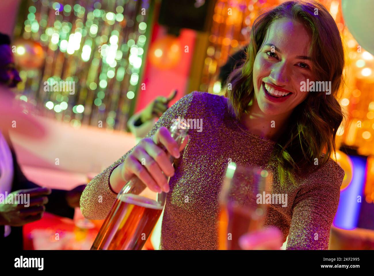 Smiling caucasian woman pouring glass of wine at nightclub. Fun, drinking, going out and party concept. Stock Photo