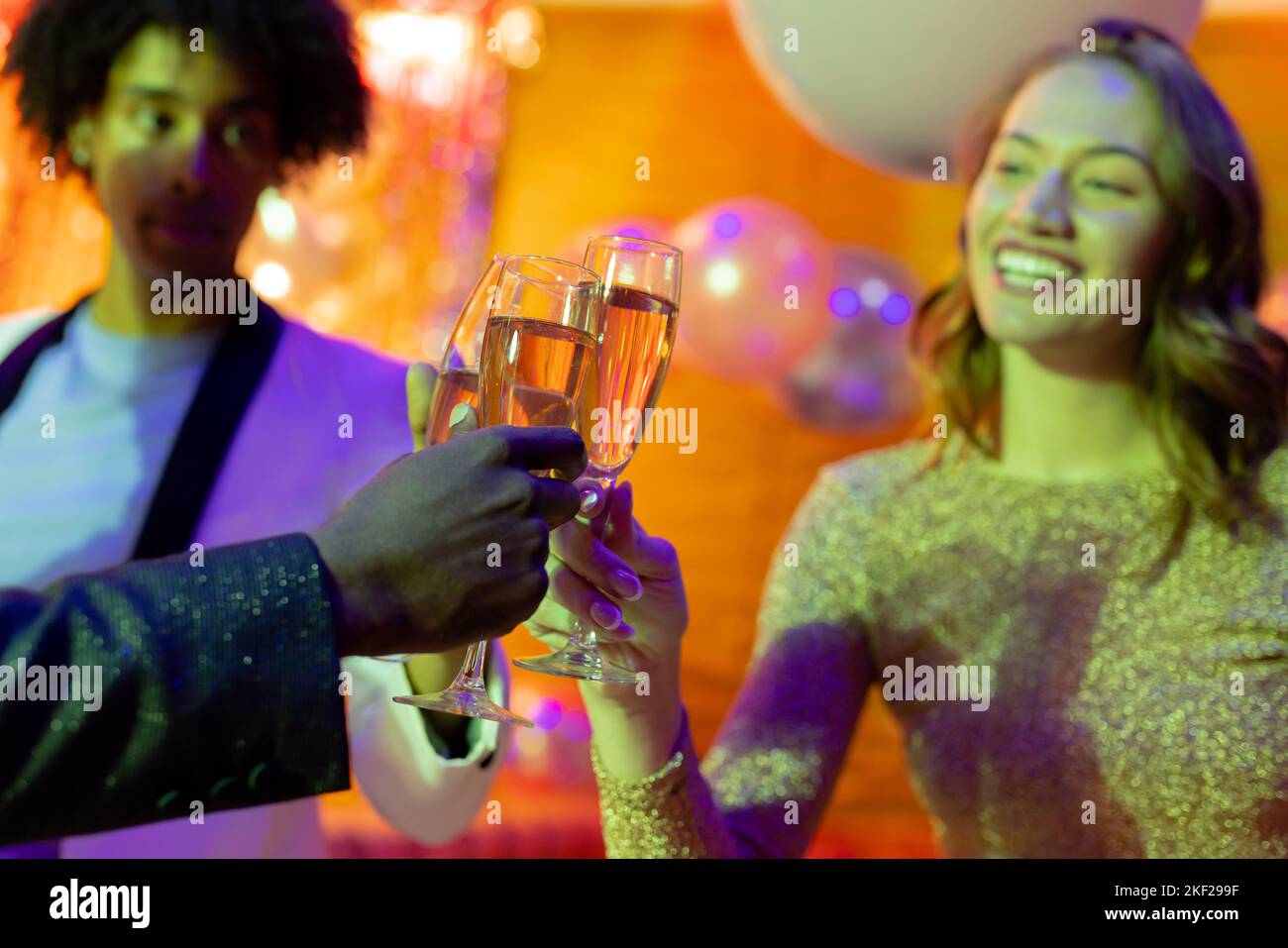 Three happy, diverse male and female friends making a toast with glasses of champagne at nightclub Stock Photo