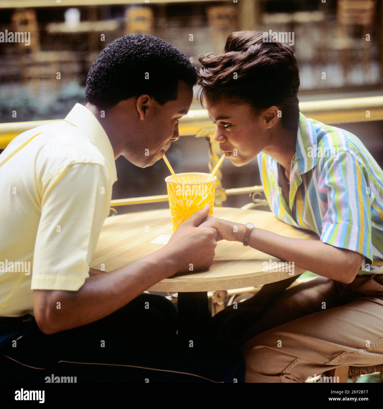 1980s ROMANTIC AFRICAN-AMERICAN COUPLE BOY AND GIRL FACE TO FACE HOLDING HANDS SHARING A SOFT DRINK WITH TWO STRAWS - kf20615 TEU001 HARS OLD FASHION 1 STYLE COMMUNICATION YOUNG ADULT STRONG JOY LIFESTYLE FEMALES COPY SPACE FRIENDSHIP HALF-LENGTH LADIES PERSONS CARING MALES TEENAGE GIRL TEENAGE BOY STRAWS DATING SUCCESS HAPPINESS LEISURE AFRICAN-AMERICANS AFRICAN-AMERICAN EXCITEMENT BLACK ETHNICITY HOLDING HANDS TO ATTRACTION RELATIONSHIPS FACE TO FACE CONNECTION COURTSHIP CONCEPTUAL CONSUME CONSUMING HYDRATION PERSONAL ATTACHMENT POSSIBILITY AFFECTION EMOTION REFRESHING SOCIAL ACTIVITY Stock Photo