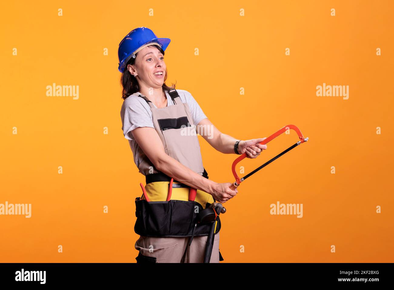 Woman renovating expert holding hand saw and using tool belt, working