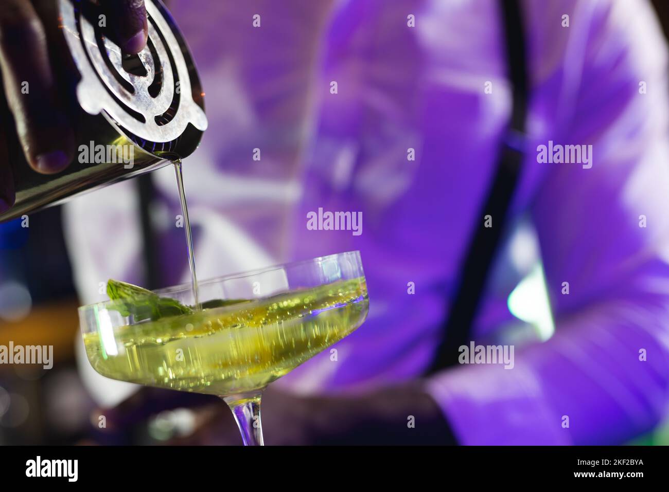 Midsection of african american barman pouring green cocktail at the bar of a nightclub Stock Photo