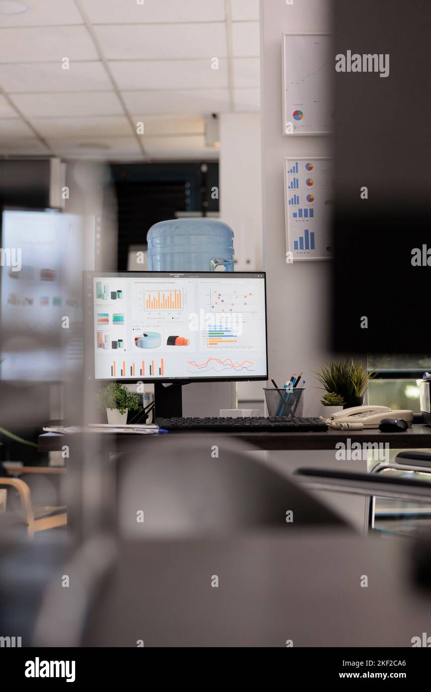 Marketing department of a company with market growth graphics and sales analysis on a desktop computer monitor. Empty office with no staff working during break time. Stock Photo