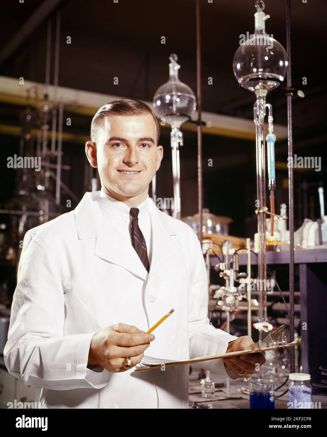 1960s SMILING MAN CHEMISTRY PROFESSOR LOOKING AT CAMERA HOLDING CLIPBOARD CONDUCTING A TITRATION CALCULATION BIOLOGY SCIENCE - kl2302 HAR001 HARS LIFESTYLE LABORATORY COPY SPACE HALF-LENGTH PERSONS BIOLOGY MALES PROFESSION OSCILLOSCOPE EYE CONTACT PROFESSOR OCCUPATION CHEERFUL DISCOVERY UNIVERSITIES CHEMIST SCIENTIFIC CAREERS EXCITEMENT INSTRUCTOR KNOWLEDGE PROGRESS INNOVATION OPPORTUNITY AUTHORITY CONDUCTING OCCUPATIONS SMILES CALCULATION HIGH TECH HIGHER EDUCATION TITRATION GLASSWARE CONTROLS EDUCATOR JOYFUL COLLEGES EDUCATING EDUCATORS IDEAS INSTRUCTORS MID-ADULT MID-ADULT MAN PRECISION Stock Photo