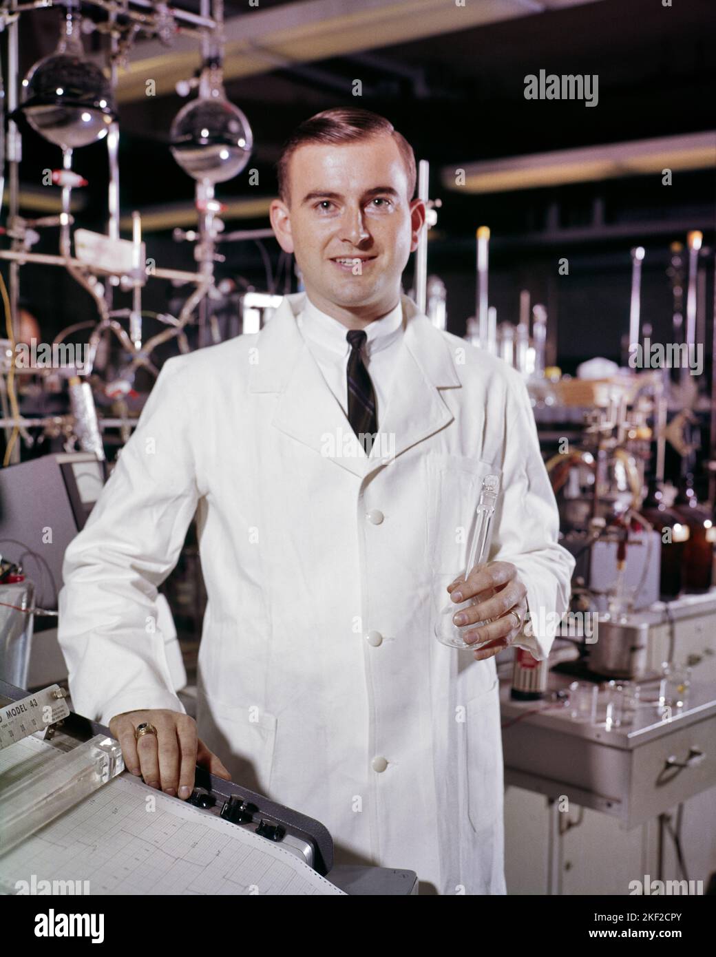 1960s PORTRAIT OF CHEMISTRY TEACHER WITH HANDS ON OSCILLOSCOPE CONTROLS HOLDING GLASSWARE CHEMIST SCIENTIST LOOKING AT CAMERA - kl2306 HAR001 HARS LIFESTYLE LABORATORY COPY SPACE HALF-LENGTH PERSONS BIOLOGY MALES PROFESSION OSCILLOSCOPE EYE CONTACT PROFESSOR OCCUPATION CHEERFUL DISCOVERY UNIVERSITIES CHEMIST SCIENTIFIC CAREERS EXCITEMENT INSTRUCTOR KNOWLEDGE PROGRESS INNOVATION OPPORTUNITY AUTHORITY CONDUCTING OCCUPATIONS SMILES CALCULATION HIGH TECH HIGHER EDUCATION TITRATION GLASSWARE CONTROLS EDUCATOR JOYFUL COLLEGES EDUCATING EDUCATORS IDEAS INSTRUCTORS MID-ADULT MID-ADULT MAN PRECISION Stock Photo