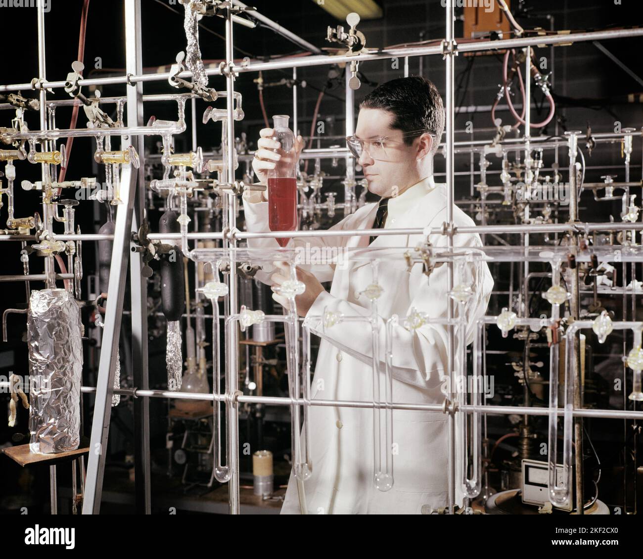 1960s MAN CHEMIST IN LAB CHECKING MEASUREMENT OF VOLUME STANDING ON VACUUM SYSTEM OF GLASS EQUIPMENT - kl2323 HAR001 HARS MEASUREMENT GOALS OCCUPATION UNIVERSITIES CHEMIST SCIENTIFIC CAREERS IN OF OCCUPATIONS HIGHER EDUCATION COLLEGES MID-ADULT MID-ADULT MAN PRECISION SOLUTIONS YOUNG ADULT MAN AMID CAUCASIAN ETHNICITY HAR001 LABORATORIES LABS OLD FASHIONED VOLUME Stock Photo