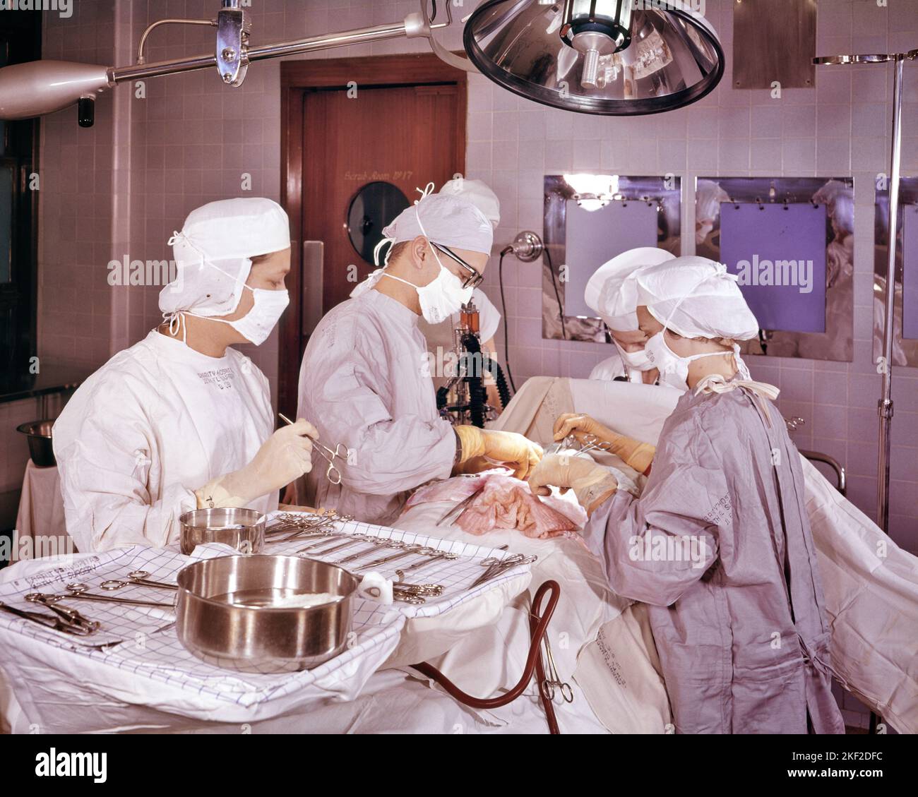 1960s SURGEON AND SUPPORTING STAFF PERFORMING A THORACIC OR ABDOMINAL SURGERY IN A HOSPITAL OPERATING ROOM - km356 GRD001 HARS COPY SPACE HALF-LENGTH LADIES PERSONS CARING MALES PROFESSION CONFIDENCE HEALTHCARE PERFORMING SURGERY SKILL OCCUPATION SKILLS OPERATING PREVENTION PROVIDER HIGH ANGLE PROVIDERS PRACTITIONERS STERILE HEALING AND DIAGNOSIS SURGICAL CAREERS PHYSICIANS HEALTH CARE IMPAIRMENT OCCUPATIONS SURGEON TREATMENT HEALER PHYSICIAN PRACTITIONER OR SUPPORTING ABDOMINAL COOPERATION O.R. OP PRECISION PROFESSIONALS STAFF TOGETHERNESS CAUCASIAN ETHNICITY DISEASE OLD FASHIONED Stock Photo