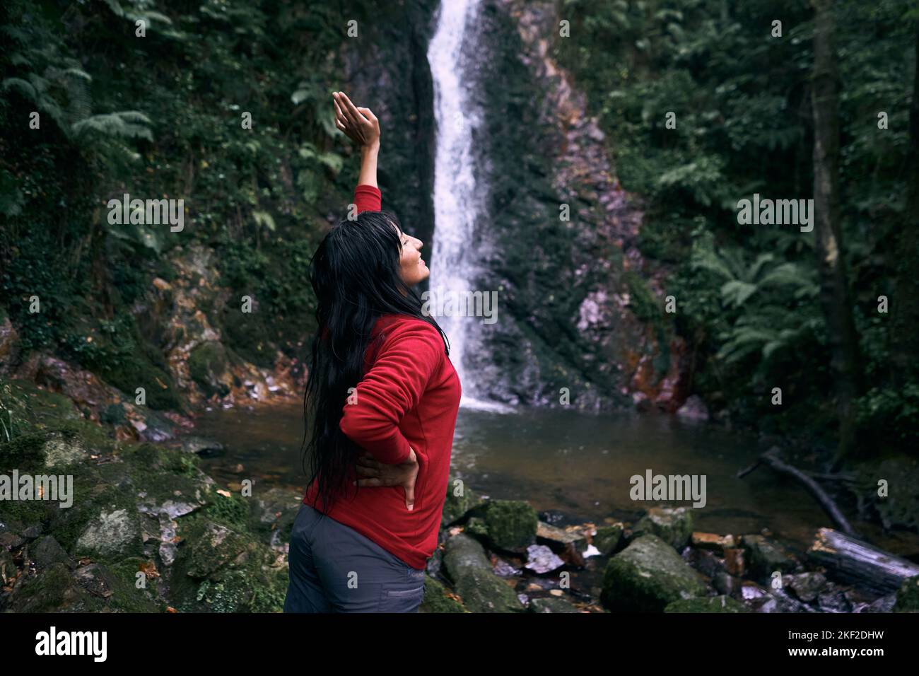 latin young woman with long hair with her left arm raised and her right