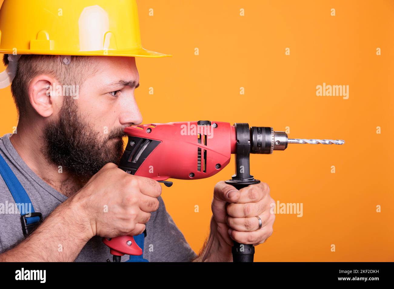 Professional builder drilling holes with electric nail gun, using power drill to work on house