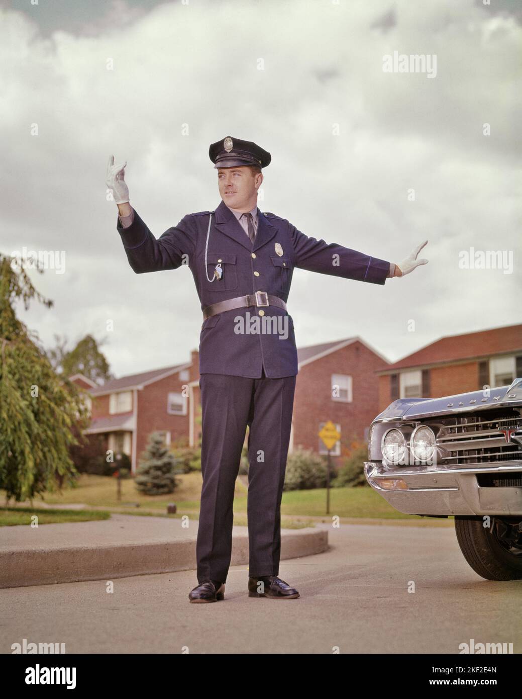 1960s STANDING TRAFFIC POLICEMAN STOPPING ONE CAR WITH HALT GESTURE AND ENCOURAGING ONCOMING TRAFFIC WITH OTHER HAND AND WHISTLE - kp850 HAR001 HARS LIFESTYLE JOBS COPY SPACE FULL-LENGTH PERSONS AUTOMOBILE MALES ORDER OFFICER PROFESSION GESTURING TRANSPORTATION COP SKILL OCCUPATION PROTECT SKILLS COURAGE AND AUTOS CAREERS LEADERSHIP LOW ANGLE DIRECTION AUTHORITY GESTURES OCCUPATIONS UNIFORMS AUTOMOBILES HALT STOPPING VEHICLES ONCOMING OFFICERS POLICEMEN WHISTLES COPS ENCOURAGING MID-ADULT MID-ADULT MAN BADGE BADGES CAUCASIAN ETHNICITY HAR001 OLD FASHIONED Stock Photo