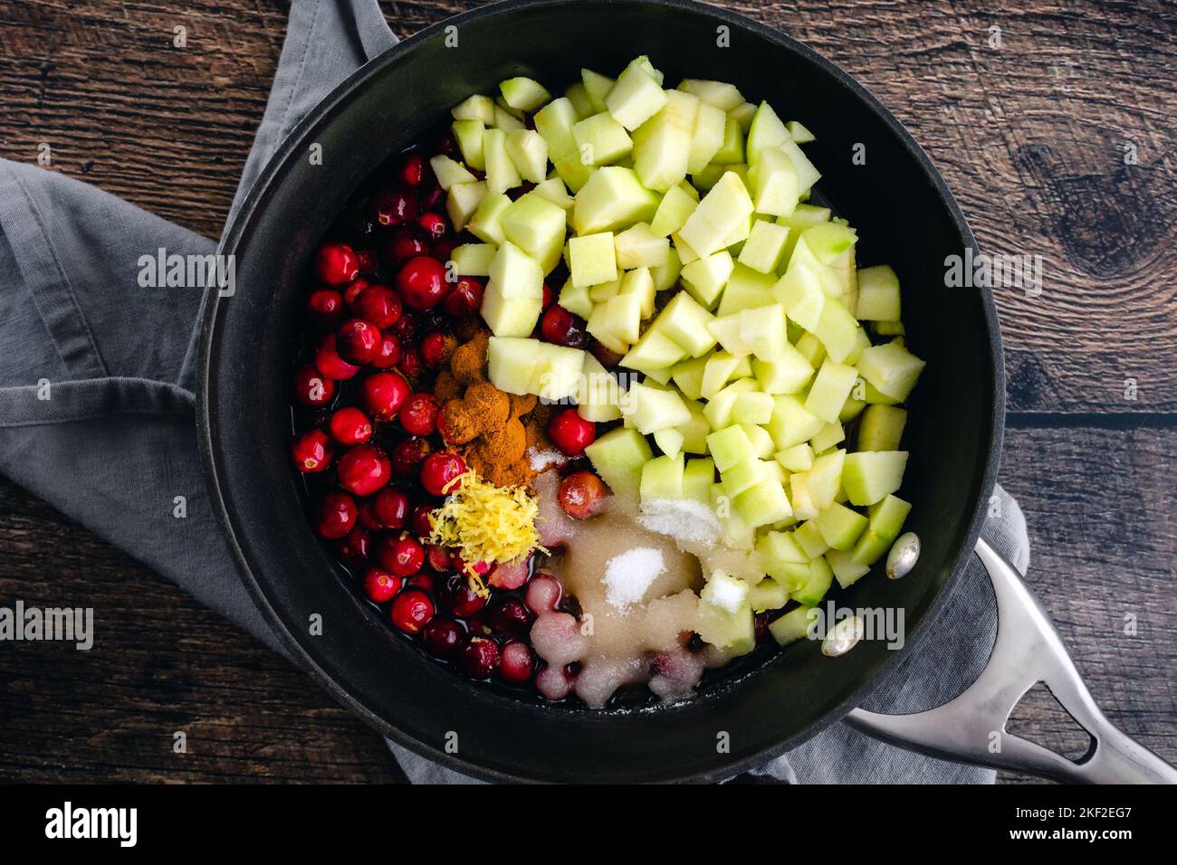 Apple Cranberry Sauce with Cider & Cinnamon Ingredients in a Saucepan: Overhead view of raw cranberry sauce ingredients in a small pot Stock Photo