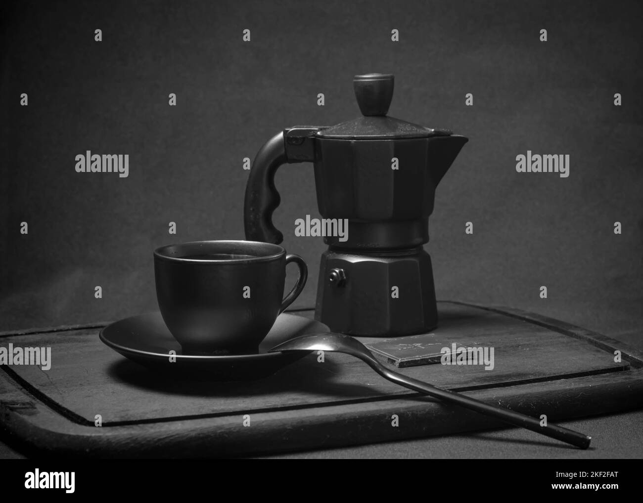 Italian coffee set. Cup of hot espresso, moka pot on a rustic wooden board, dark background, selective focus. Still life, dark photography. Stock Photo
