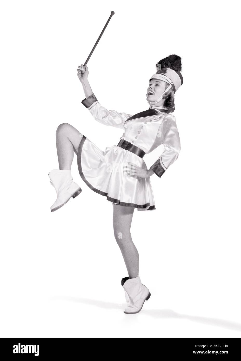 1960s SMILING GIRL MAJORETTE WITH BATON WEARING BAND UNIFORM WITH PLUMED HAT BOOTS SHORT SKIRT POSING WITH ONE LEG RAISED - p2279 DEB001 HARS MARCHING CELEBRATION FEMALES STUDIO SHOT COPY SPACE FULL-LENGTH LADIES PERSONS TEENAGE GIRL ENTERTAINMENT CONFIDENCE LEADING B&W SCHOOLS BATON VICTORY UNIVERSITIES RECREATION HIGH SCHOOL MARCH POSING HIGH SCHOOLS HIGHER EDUCATION PLUMED TEENAGED COLLEGES DEB001 MAJORETTE JUVENILES YOUNG ADULT WOMAN BLACK AND WHITE CAUCASIAN ETHNICITY HIGH STEPPING MARCHER OLD FASHIONED PARADES Stock Photo