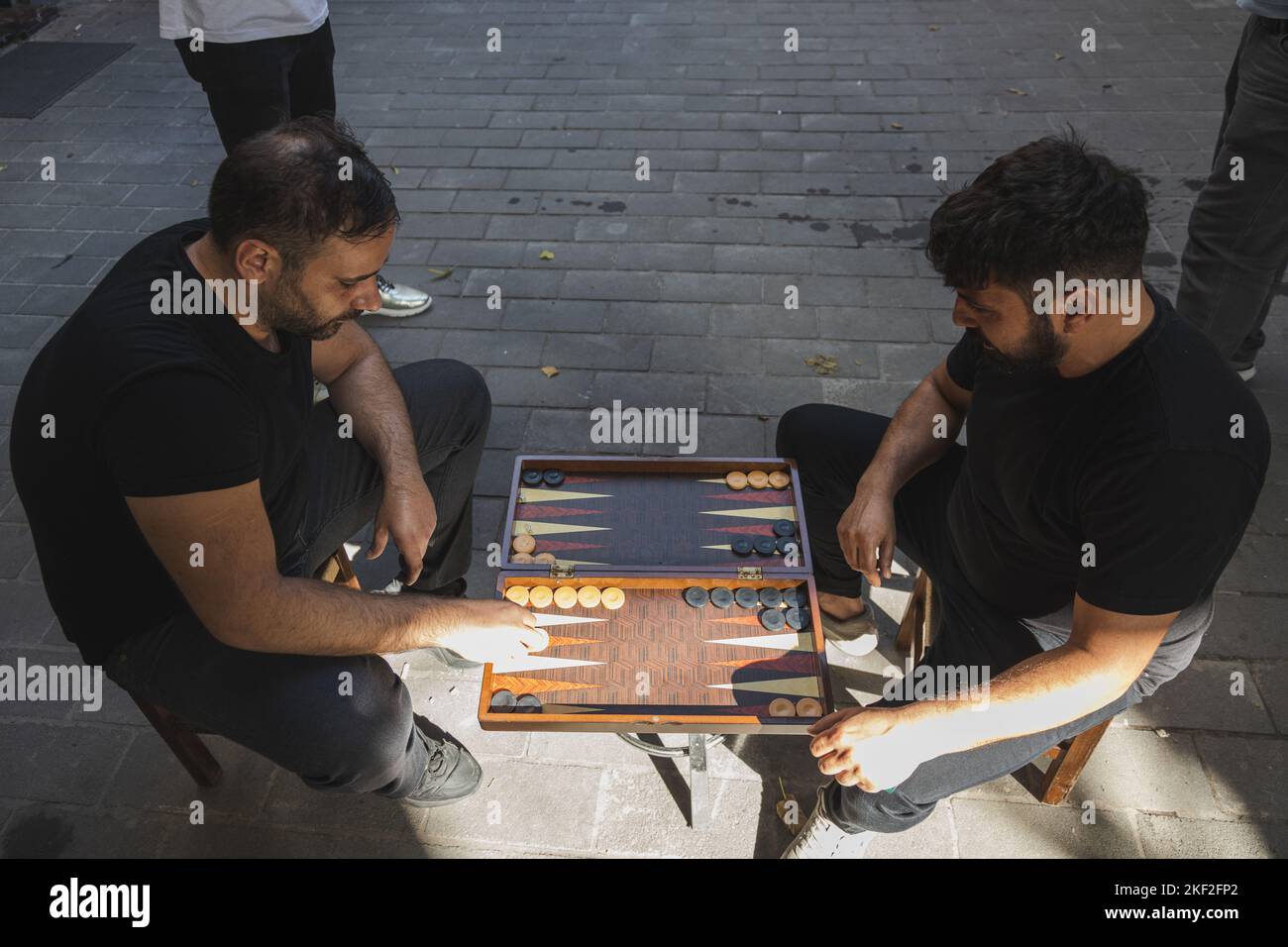 Istanbul, Turkey - October 1 2022: Two Turkish men on the streets of Istanbul play a friendly match of the traditional board game backgammon. Stock Photo
