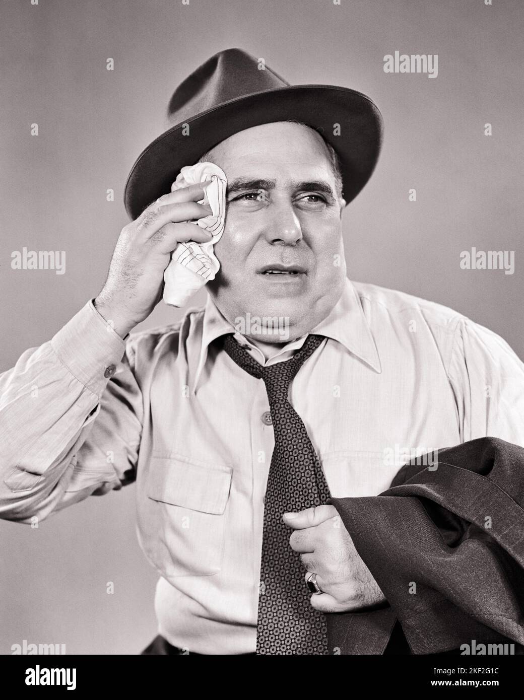 1940s 1950s UNHAPPY BUSINESSMAN WEARING HAT CARRYING SUIT JACKET OVER ARM WIPING SWEAT FROM HIS BROW ON HOT SUMMER DAY COMMUTER - s11139 HAR001 HARS OLD FASHION 1 FACIAL FEAR SAFETY WORRY TIRED LIFESTYLE EXHAUSTED STUDIO SHOT MOODY HEAT ILLNESS HOME LIFE COPY SPACE HALF-LENGTH PERSONS DANGER MALES RISK SWEAT EXPRESSIONS TROUBLED HAZARD SWEATING MIDDLE-AGED B&W CONCERNED SADNESS MIDDLE-AGED MAN SUMMERTIME COMMUTE WIPING DANGEROUS HIS EXCITEMENT EXHAUSTION RISKY HAZARDOUS MOOD UNHEALTHY PERIL UNSAFE CONCEPTUAL GLUM UNCOMFORTABLE JEOPARDY WILTED BROW FATIGUE MISERABLE PERSPIRATION SEASON Stock Photo