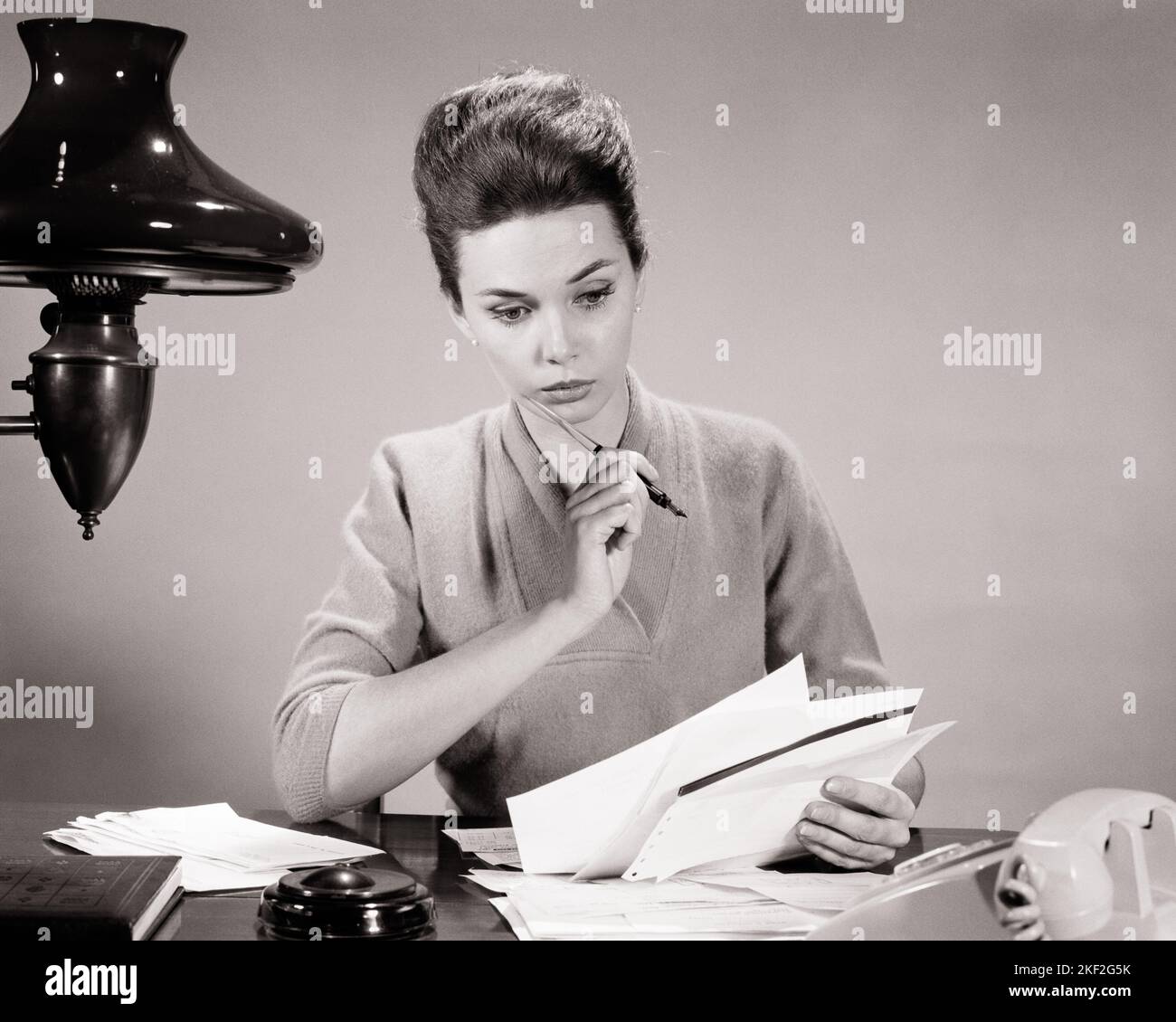 1950s 1960s BRUNETTE WOMAN AT HOME DESK PEN IN HAND PONDERING HANDFUL OF INVOICES BILLS DOCUMENTS PAPER WORK  - s12953 HAR001 HARS HOME LIFE COPY SPACE HALF-LENGTH LADIES PERSONS CARING B&W BRUNETTE GOALS SKILL OCCUPATION DOCUMENTS SKILLS DISCOVERY KNOWLEDGE OFFICE WORKER OPPORTUNITY OCCUPATIONS PONDERING CONNECTION GAL FRIDAY ADMINISTRATOR SECRETARIES PAPER WORK AMANUENSIS GROWTH HANDFUL SOLUTIONS TASK YOUNG ADULT WOMAN BLACK AND WHITE CAUCASIAN ETHNICITY CLERICAL HAR001 INVOICES OLD FASHIONED Stock Photo
