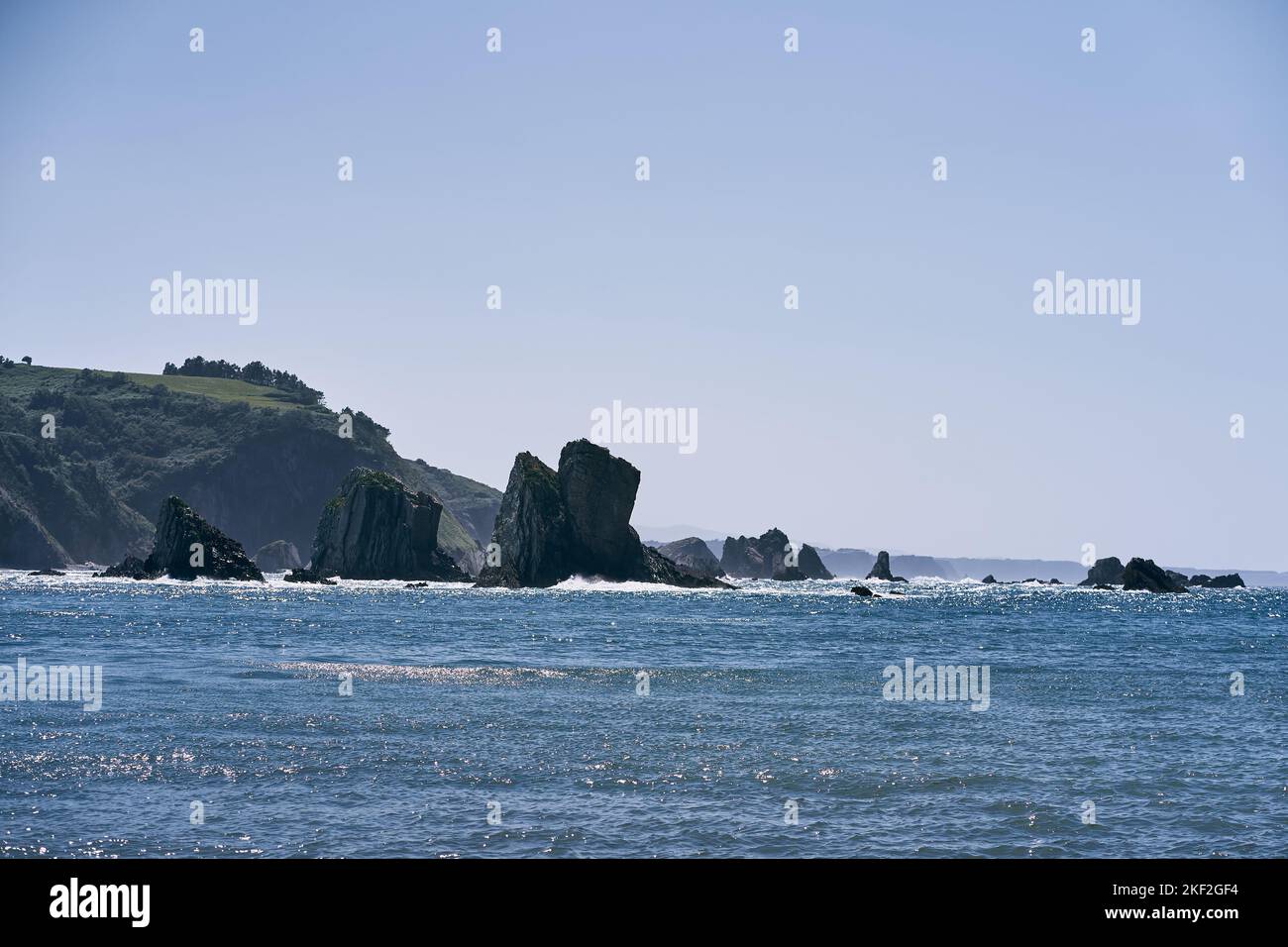 landscape of the cantabrian sea shining illuminated by the sun with big rocks near the cliffs in a calm and lonely place, asturias, spain Stock Photo