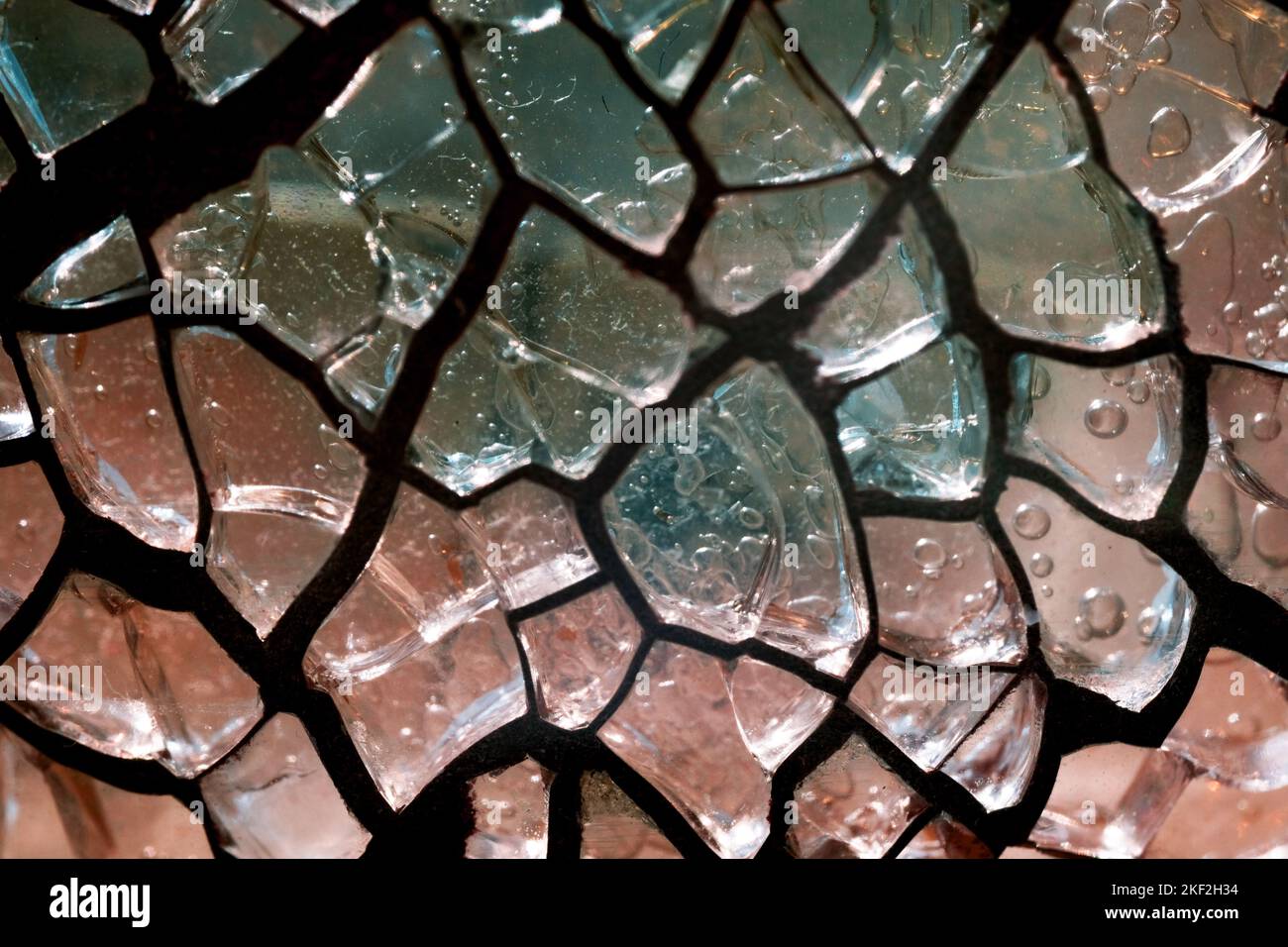 Cracked, coloured or stained glass with light shining through. Macro