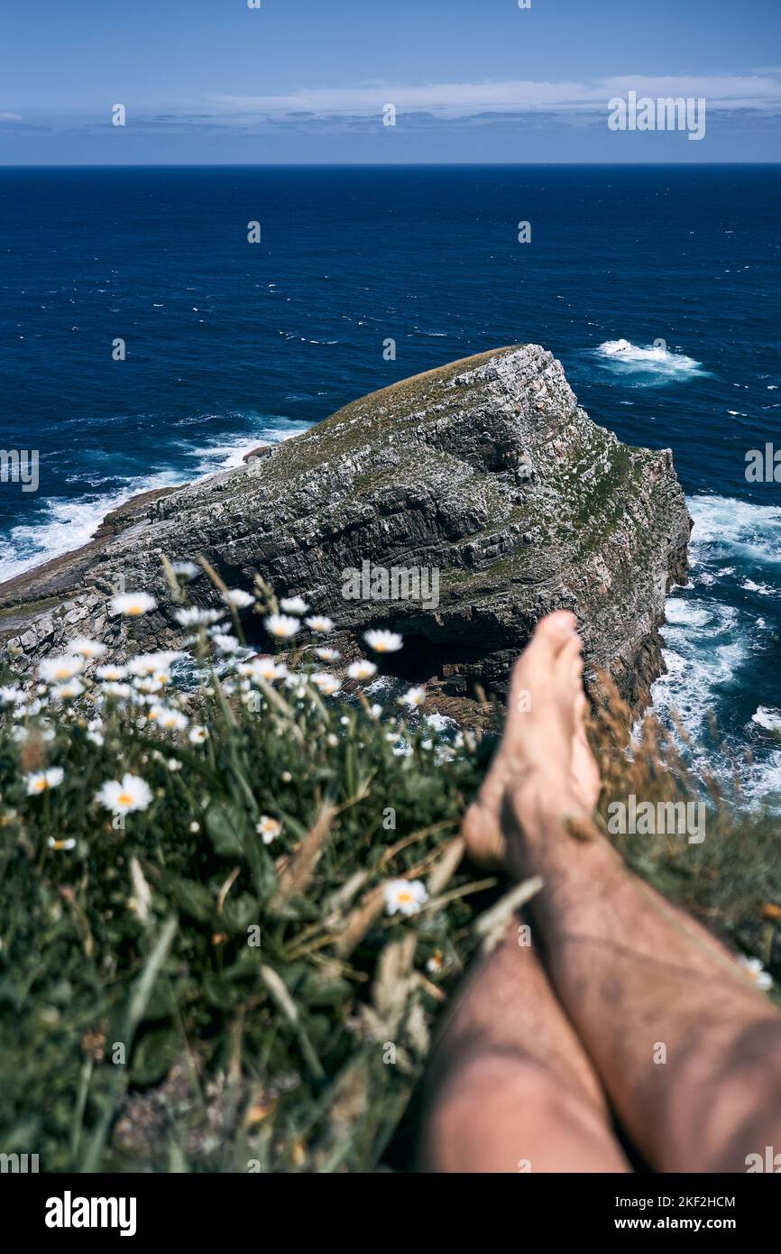 unfocused legs and feet of a caucasian boy on the big rocks of the cliffs next to the strong waves of the cantabrian sea, asturias, spain Stock Photo