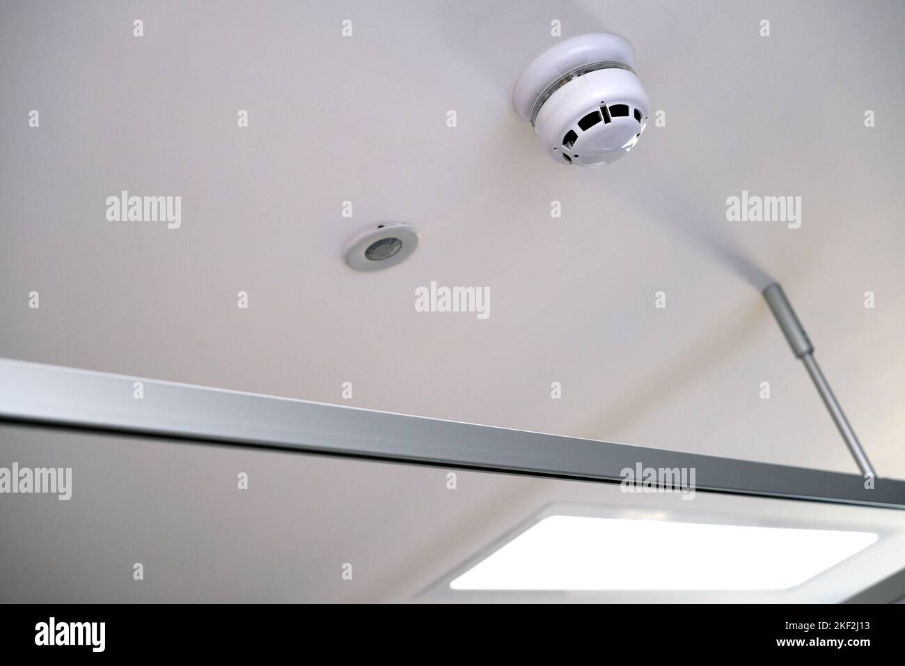Ceiling fittings and fixtures in modern clinical setting. Smoke or carbon monoxide detector and alarm and emergency lighting LED. Metal and plastic Stock Photo