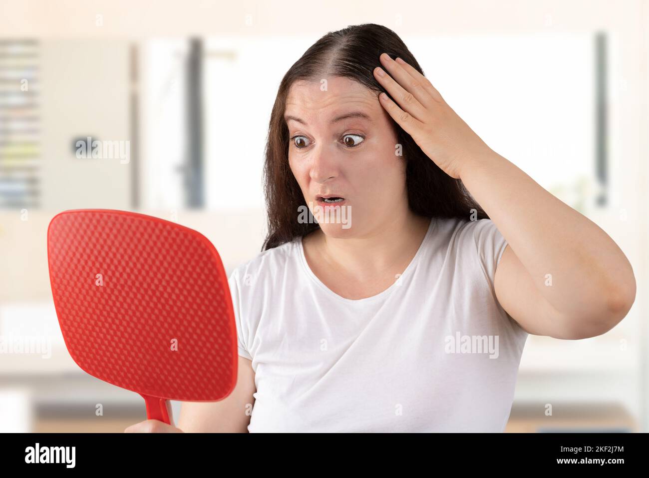 Upset middle aged woman with alopecia looking at mirror, hair loss concept Stock Photo